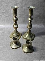 Four brass candlesticks grouped on fabric backdrop