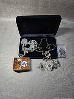 Overview of entire lot including jewelry box, necklaces, bracelet, bead box, and bagged earrings