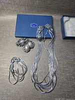 Overview showing necklace, bracelet coil, two brooches and Clowes Jewellery box