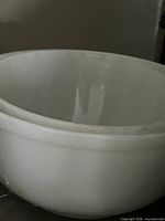 Two stacked white Pyrex glass mixing bowls