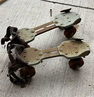 Top view of both metal skates showing adjustable plates, rust, worn straps, wheels