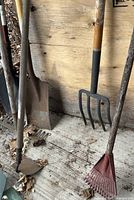 Grouping of shovel, hoe, pitchfork, red leaf rake