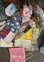 pile of assorted gift bags, wrapping paper rolls, visible PINK bag and varied prints