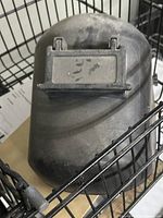 Front view of black flip-front welding helmet showing lens window and dust wear