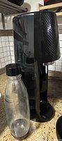 front view of black soda maker with reusable bottle