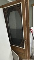 Full view of wooden screen door showing oval screen and hardware