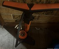 Full view of orange/black floor pump against wall