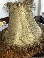 Full view of gold damask lampshade with fringe trim