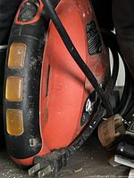 Close view of red/black jig saw right side with power cord and plug visible