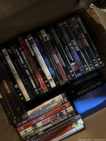 Open box showing mixed DVD and Blu-ray titles in two stacks and a horizontal row, highlighting film variety