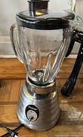 Full view of Osterizer blender showing glass jar, black lid, stainless base and power cord