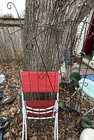 Two black metal garden trellis panels leaning against tree