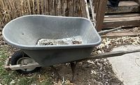 Left side view of grey plastic tub wheelbarrow, showing wooden handles and pneumatic tire