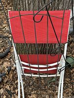 Front view of folded red mesh sling chair with white metal frame