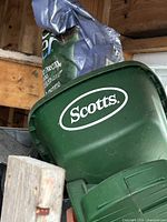 Close view of Scotts handheld spreader and bag behind