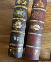 Spines of both faux books showing gold filigree, butterflies, floral motifs