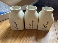 Front view of three cream ceramic vases with Laugh, Love, Live script