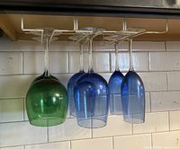 Five colored stemmed glasses hanging from rack