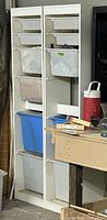 full view of tall white organizer with bins in workshop