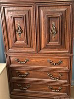 Front view of tall dresser showing cabinet doors and three drawers