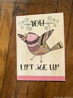 Front view of wooden plaque showing bird design and text