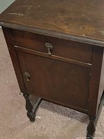 Nightstand front view showing drawer, cabinet door, turned legs