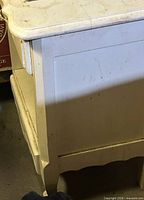 Right side and top of distressed white nightstand showing curved edge and paint wear