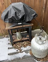 grill on stand with propane tank and watering can