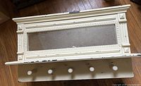 Front view of coat rack showing mirror, five pegs, distressed paint