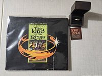 Front of softcover film book alongside ring box and tag