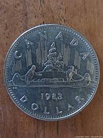 Reverse side of 1983 Canadian Voyageur dollar showing full design and date
