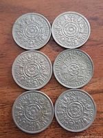 Six two-shilling coins grouped on wooden surface