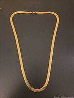 Full view of gold-tone herringbone necklace laid flat