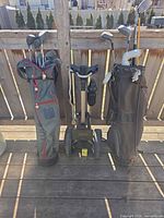 Two golf bags filled with clubs and golf caddy in center