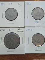 Four British shilling coins in flips laid out 2x2