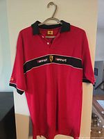 Front view of red Ferrari polo shirt hanging on hanger