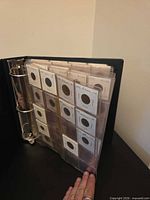 Binder open showing plastic pages with 2×2 coin flips