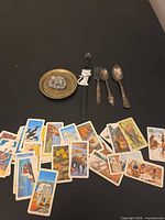 Group shot of all items: brass plate with frog figurine, cat wristwatch, three silver-plated utensils, spread of wildlife cards