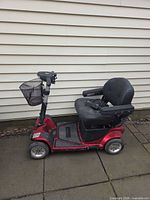Side view of red Pride Revo scooter showing seat, basket, wheels