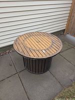 full view of round fire pit table beside siding