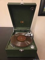 Open green suitcase gramophone with turntable and tone arm visible