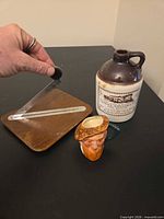 Overview of all three items: tobacco cutter, stoneware jug, figural cup