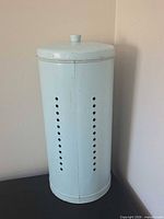 Full view of canister angled, showing height, color, lid, perforations