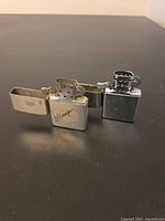 Both lighters open showing chimneys and lid mechanisms