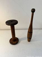 Indian club and spindle standing upright on white surface