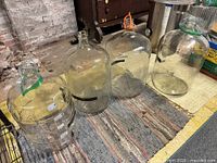 Group shot of all four clear glass carboys on floor mat