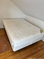Full mattress and box spring on metal frame in room corner