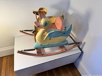 Side view of multicolor duck rocking toy showing skis and springs