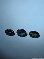 Three oval sapphires side by side on neutral background