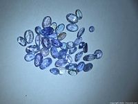 Cluster of loose faceted violet-blue Tanzanite stones on white background